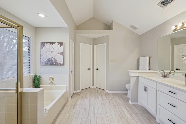 bathroom featuring a relaxing tiled tub, lofted ceiling, toilet, and vanity