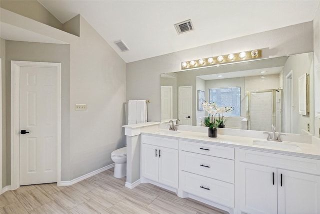 bathroom featuring vanity, vaulted ceiling, a shower with door, and toilet