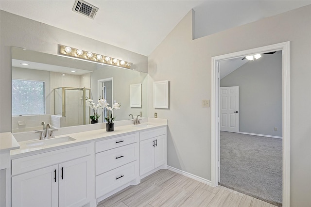 bathroom featuring walk in shower, lofted ceiling, and vanity