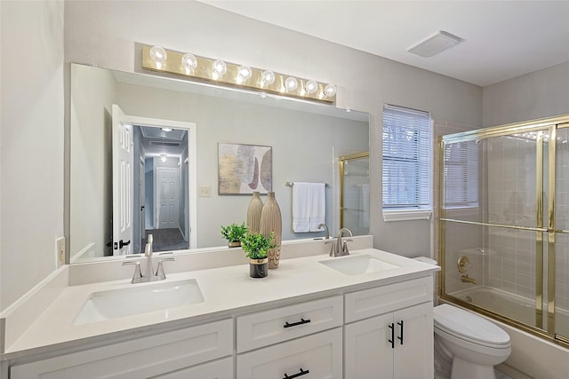 full bathroom featuring toilet, vanity, and bath / shower combo with glass door