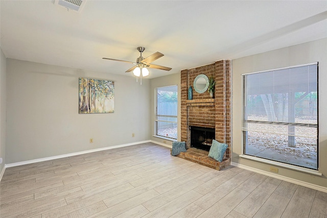 unfurnished living room featuring a brick fireplace, light hardwood / wood-style floors, and ceiling fan