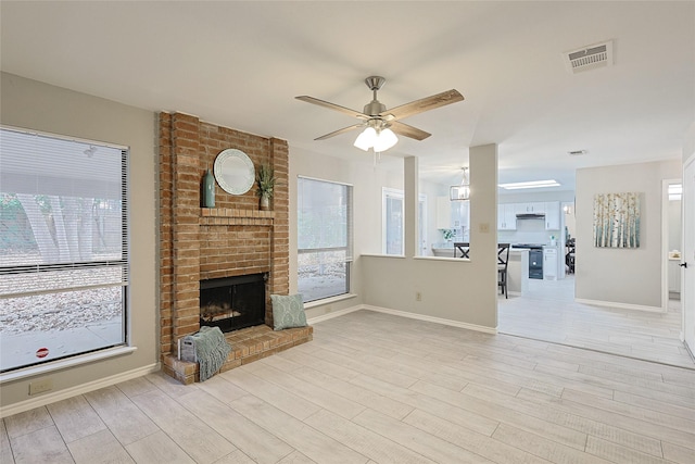 unfurnished living room featuring ceiling fan, a fireplace, and light wood-type flooring