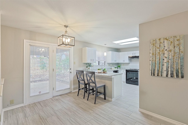 kitchen featuring black electric range oven, a breakfast bar area, white cabinetry, kitchen peninsula, and pendant lighting