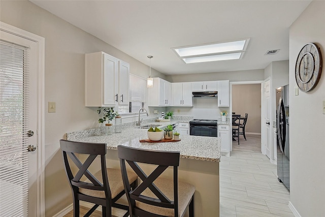 kitchen with sink, black appliances, hanging light fixtures, kitchen peninsula, and white cabinets