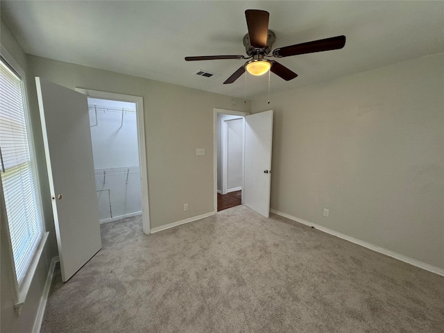 unfurnished bedroom featuring ceiling fan, light colored carpet, a spacious closet, and a closet