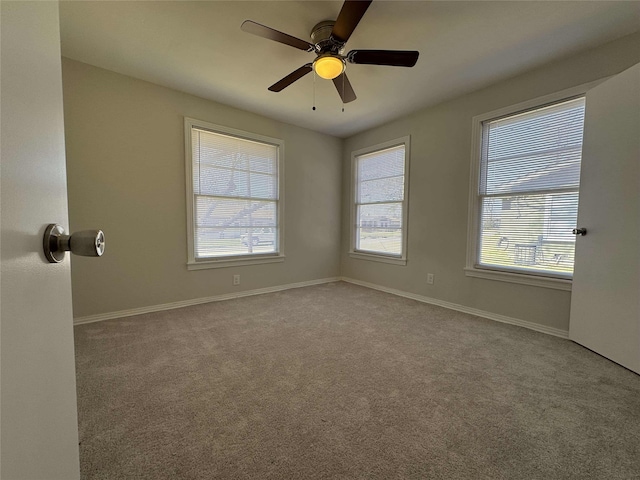 carpeted spare room featuring a ceiling fan and baseboards