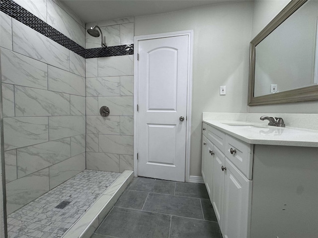 full bath with vanity, baseboards, and a tile shower