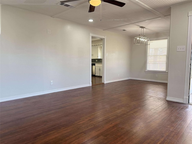 empty room featuring dark wood-style floors, visible vents, ceiling fan with notable chandelier, and baseboards