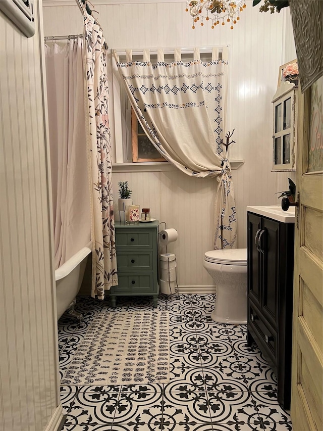 full bathroom featuring toilet, wood walls, shower / bath combo with shower curtain, tile patterned flooring, and vanity