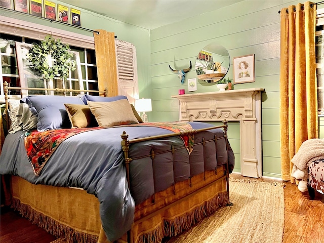 bedroom with wood walls and hardwood / wood-style flooring