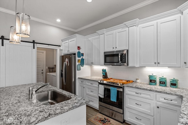 kitchen with sink, stainless steel appliances, independent washer and dryer, white cabinets, and a barn door