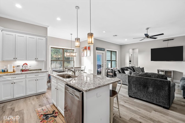 kitchen with white cabinetry, ceiling fan, light stone counters, stainless steel dishwasher, and an island with sink