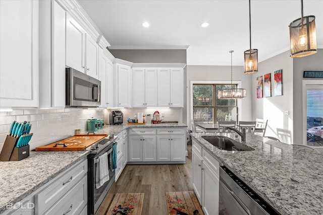 kitchen featuring light stone countertops, sink, hanging light fixtures, white cabinets, and appliances with stainless steel finishes