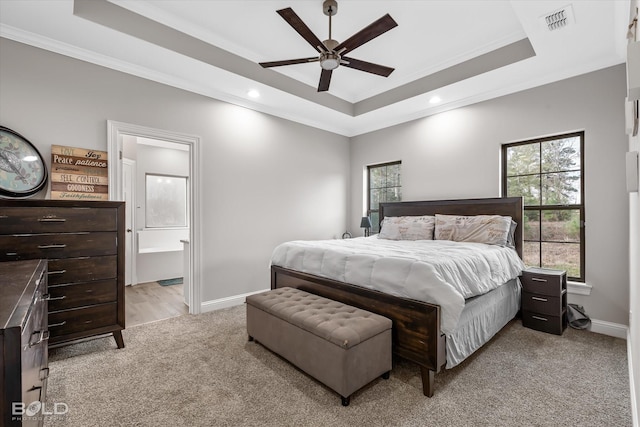 bedroom with a raised ceiling, multiple windows, ensuite bathroom, and ceiling fan