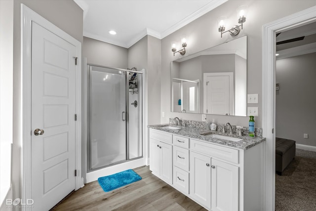 bathroom featuring ornamental molding, wood-type flooring, a shower with door, and vanity