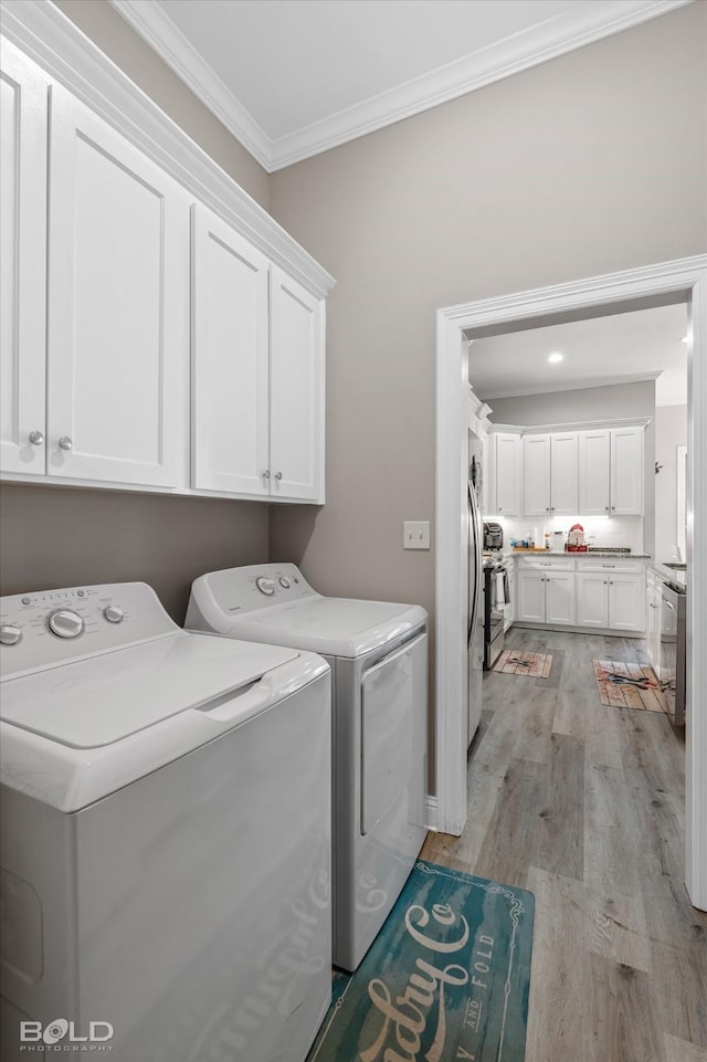 washroom featuring cabinets, ornamental molding, light wood-type flooring, and independent washer and dryer