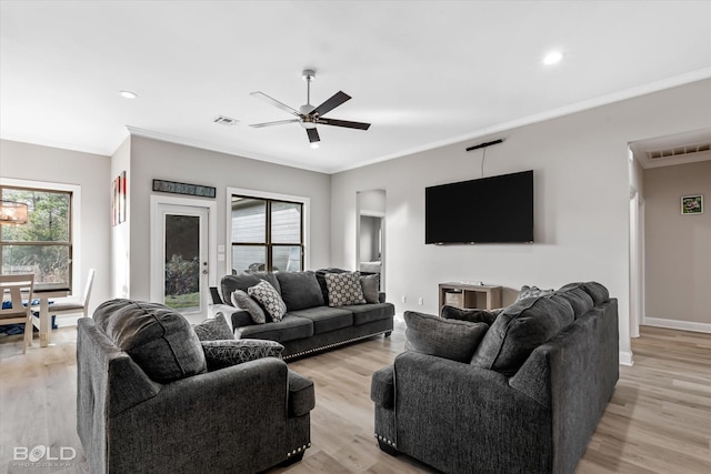 living room with ornamental molding, ceiling fan, and light wood-type flooring