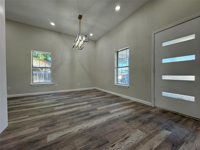 unfurnished dining area featuring plenty of natural light, dark wood-type flooring, and a high ceiling