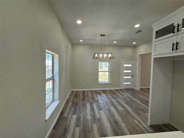 unfurnished dining area with dark hardwood / wood-style floors and a chandelier