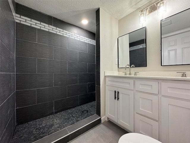 bathroom featuring a tile shower, tile patterned flooring, vanity, and a textured ceiling