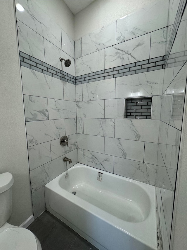 bathroom with toilet and tiled shower / bath