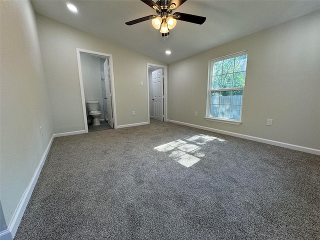 unfurnished bedroom featuring dark colored carpet, ceiling fan, ensuite bathroom, and vaulted ceiling