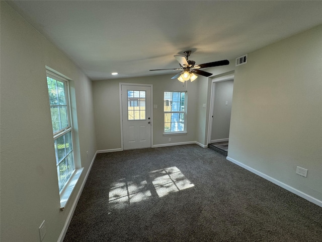 spare room with dark colored carpet, plenty of natural light, ceiling fan, and lofted ceiling