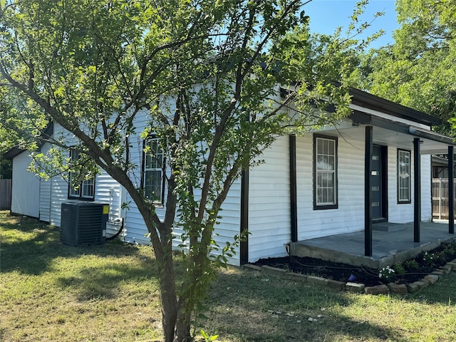 view of side of home featuring a porch, a lawn, and central air condition unit