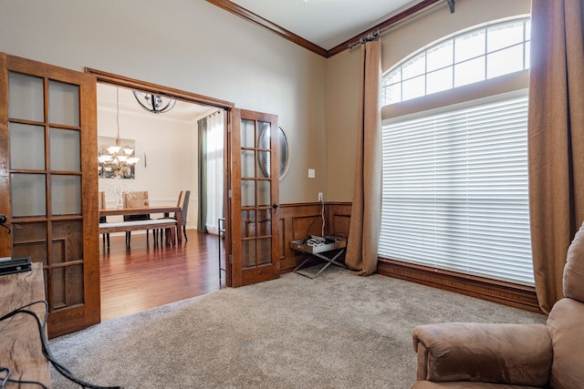 sitting room with carpet, crown molding, wooden walls, and an inviting chandelier