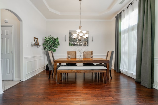 dining space with a chandelier, dark hardwood / wood-style flooring, a raised ceiling, and crown molding