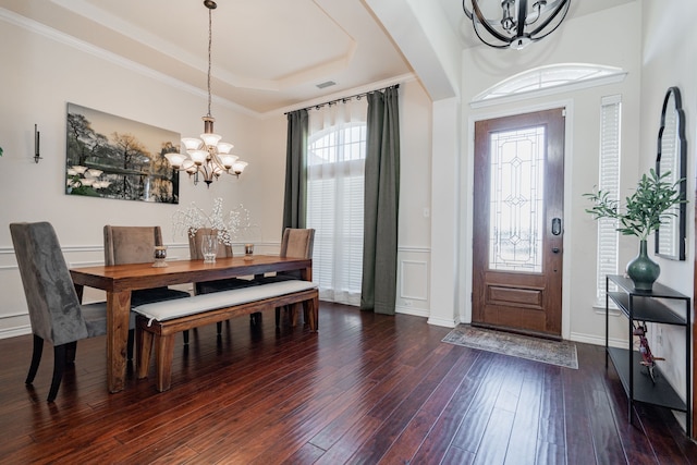 entryway featuring dark hardwood / wood-style floors, a raised ceiling, a notable chandelier, and crown molding