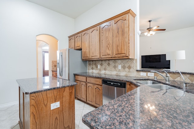 kitchen with backsplash, sink, dark stone countertops, light tile patterned floors, and stainless steel appliances