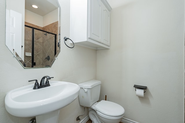 bathroom with a tile shower, sink, and toilet