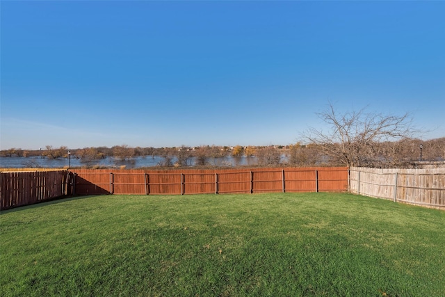 view of yard with a water view and a fenced backyard