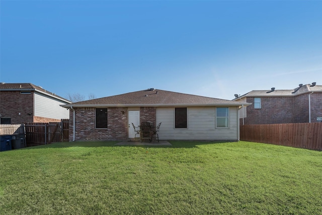 back of house with a yard, brick siding, and a fenced backyard