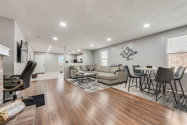 living area with recessed lighting, visible vents, light wood-style flooring, and a textured ceiling