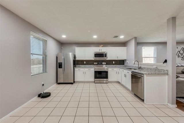 kitchen featuring light tile patterned floors, stainless steel appliances, visible vents, decorative backsplash, and a sink