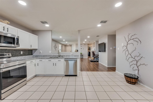 kitchen with appliances with stainless steel finishes, light tile patterned flooring, a sink, and visible vents