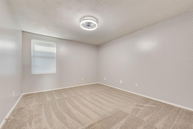 carpeted empty room featuring a textured ceiling and baseboards