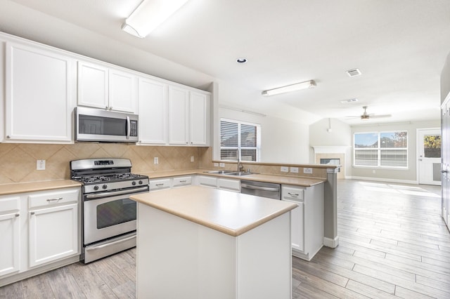 kitchen with tasteful backsplash, stainless steel appliances, sink, a center island, and white cabinetry