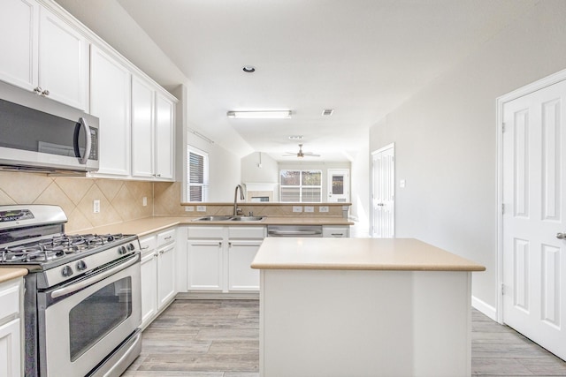 kitchen with white cabinets, appliances with stainless steel finishes, a center island, and sink