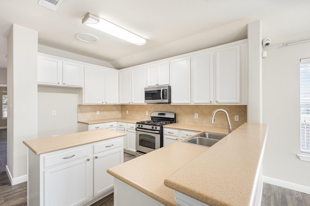 kitchen featuring backsplash, white cabinets, sink, appliances with stainless steel finishes, and kitchen peninsula