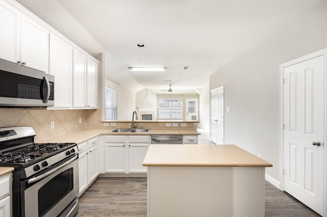 kitchen featuring stainless steel appliances, sink, white cabinets, hardwood / wood-style floors, and a center island