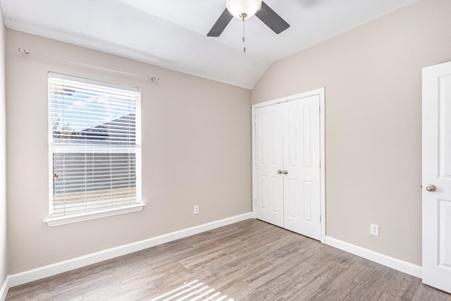 unfurnished bedroom featuring ceiling fan, a closet, lofted ceiling, and hardwood / wood-style flooring