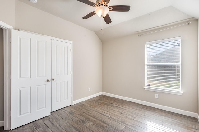 unfurnished bedroom with multiple windows, ceiling fan, a closet, and lofted ceiling