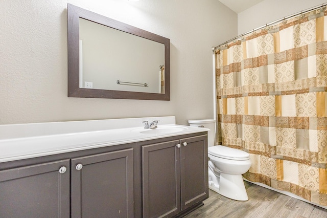 bathroom featuring hardwood / wood-style flooring, vanity, toilet, and walk in shower