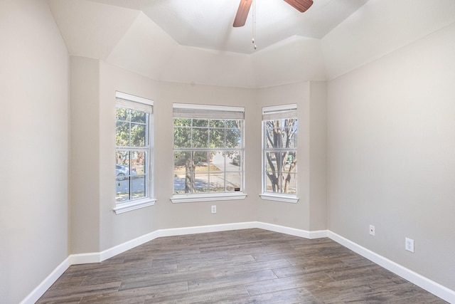 spare room with dark hardwood / wood-style flooring, a tray ceiling, and ceiling fan