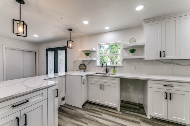 kitchen featuring tasteful backsplash, white cabinetry, sink, and hanging light fixtures