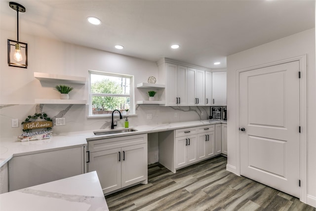 kitchen with tasteful backsplash, sink, pendant lighting, hardwood / wood-style floors, and white cabinetry