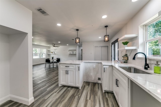 kitchen with sink, hanging light fixtures, ceiling fan, light stone counters, and white cabinetry